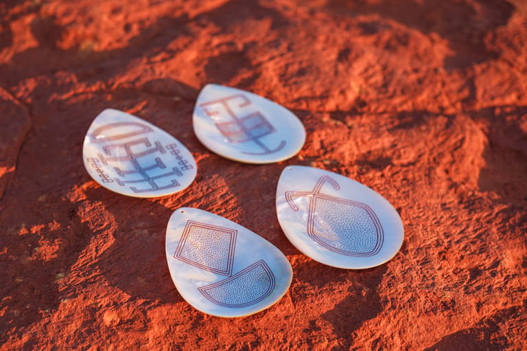 Four translucent flexible electronic devices arranged on rust-coloured textured surface.