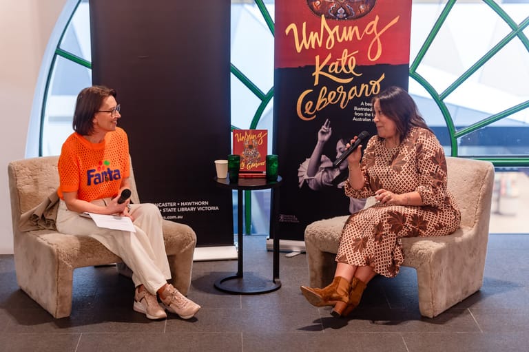 Two women seated in armchairs during a live interview or talk show discussion.