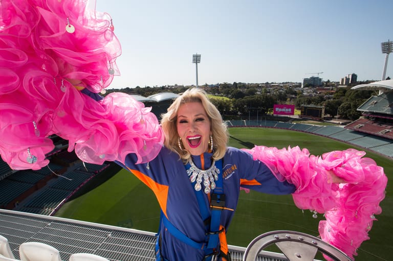 Woman in blue jacket surrounded by bright pink decorations at an outdoor sporting venue.