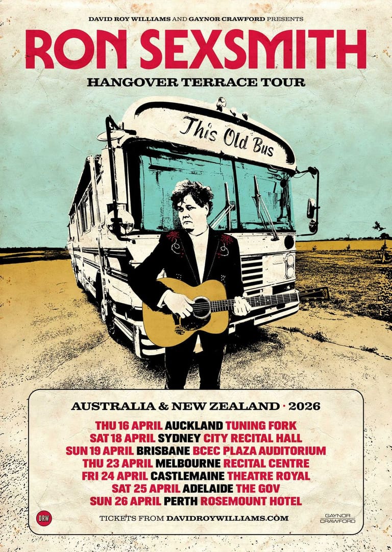 Musician with acoustic guitar stands beside a vintage bus labelled "This Old Bus" against a desert landscape for the Hangover Terrace Tour.