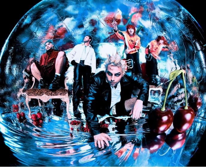 Multiple performers in stylised costumes positioned within a glowing blue spherical digital environment on stage.