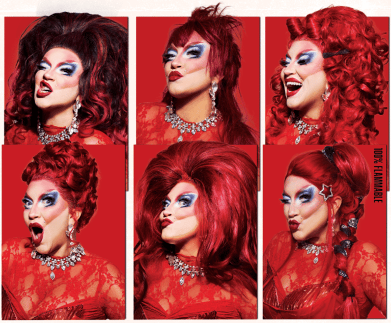 Six drag performers with bold makeup and red wigs pose against a vibrant red backdrop, wearing jewelled accessories and red garments.
