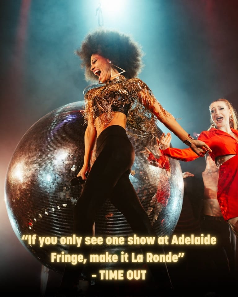 Performers in sequinned costumes pose playfully around a large glittering disco ball under theatrical blue and red lighting.