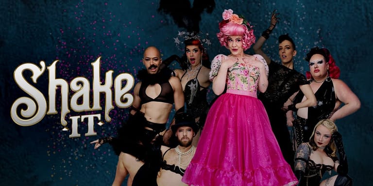 Performers in vibrant costumes gather around a central figure in a hot-pink tulle skirt against a starry blue backdrop.