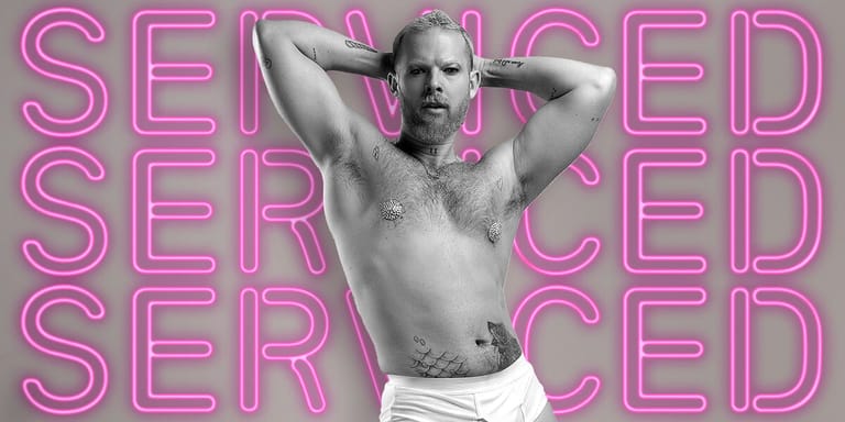 Shirtless performer with hands behind head posed against neon pink "SERVICED" text on grey background.