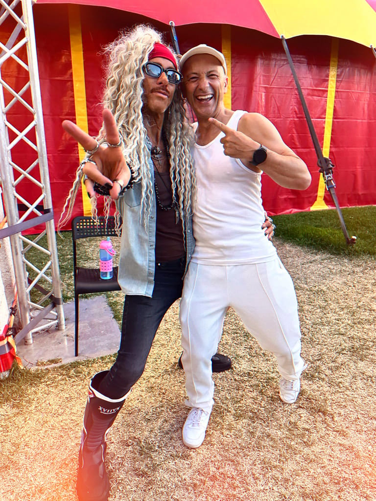 Two audience members in 90s-themed costumes pose enthusiastically outside a red circus tent during Matt Hale's hypnotist show.