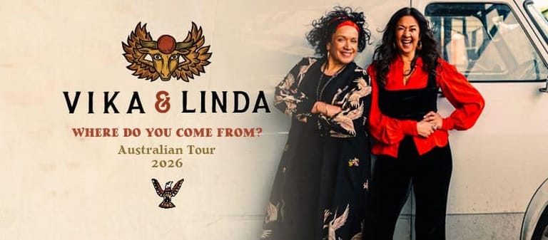 Two women stand beside a vintage caravan for the Vika & Linda "Where Do You Come From?" Australian tour.
