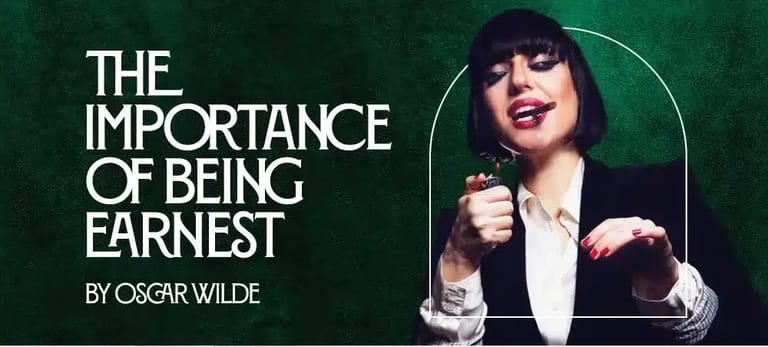 Woman with dark hair and red lipstick holding a microphone against green background with Oscar Wilde quote.