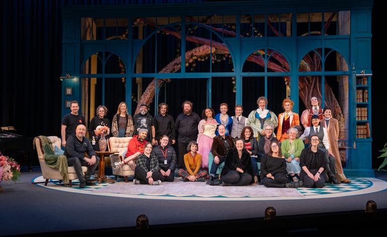 Full cast of The Importance of Being Earnest assembled on stage before a blue Victorian-style interior set.