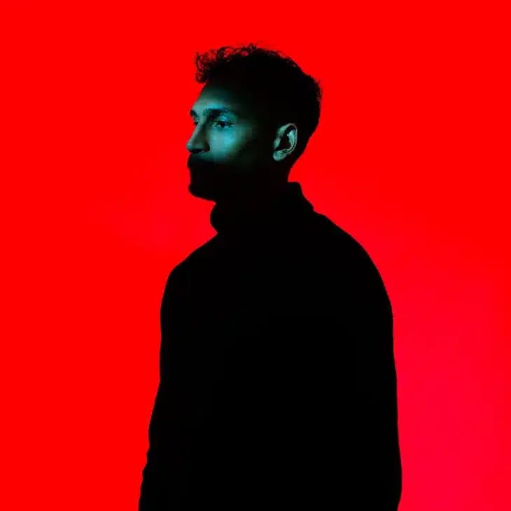 Person silhouetted in profile against a vibrant red background.