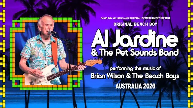 Man with shaved head and tattoos playing guitar against purple stage backdrop with neon-framed screen.