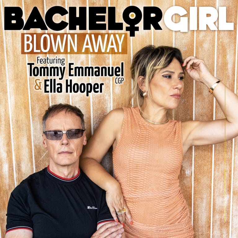 Two musicians pose against a wooden backdrop for the Bachelor Girl single "Blown Away" featuring Tommy Emmanuel and Ella Hooper.