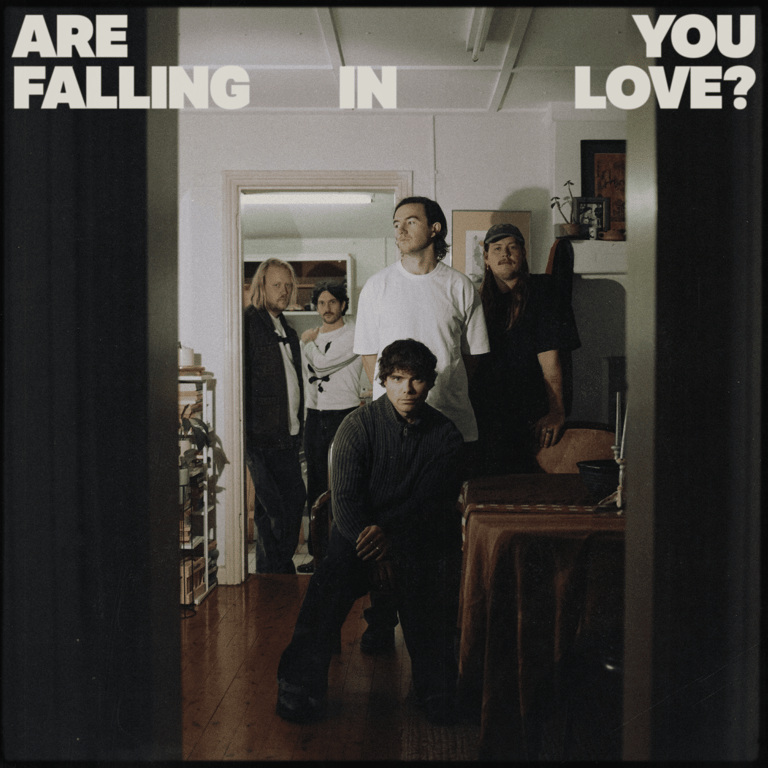 Five band members posed in a residential room with text overlay reading "Are falling in love?