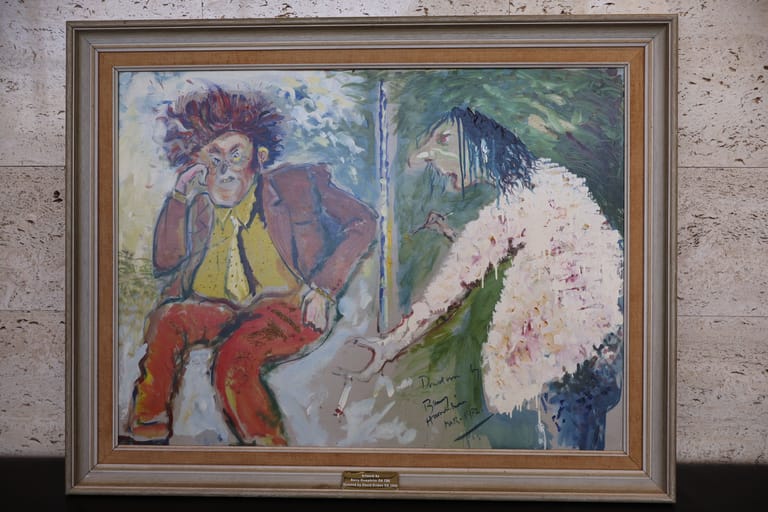 Two framed paintings side by side: a figure in red and yellow on the left, and white flowers on green foliage on the right.