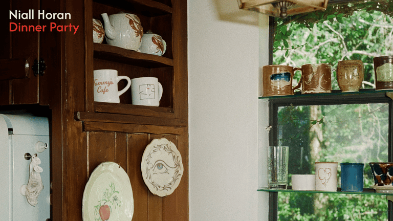 Decorative plates and kitchenware displayed on wooden wall shelving in a vintage-styled interior setting.