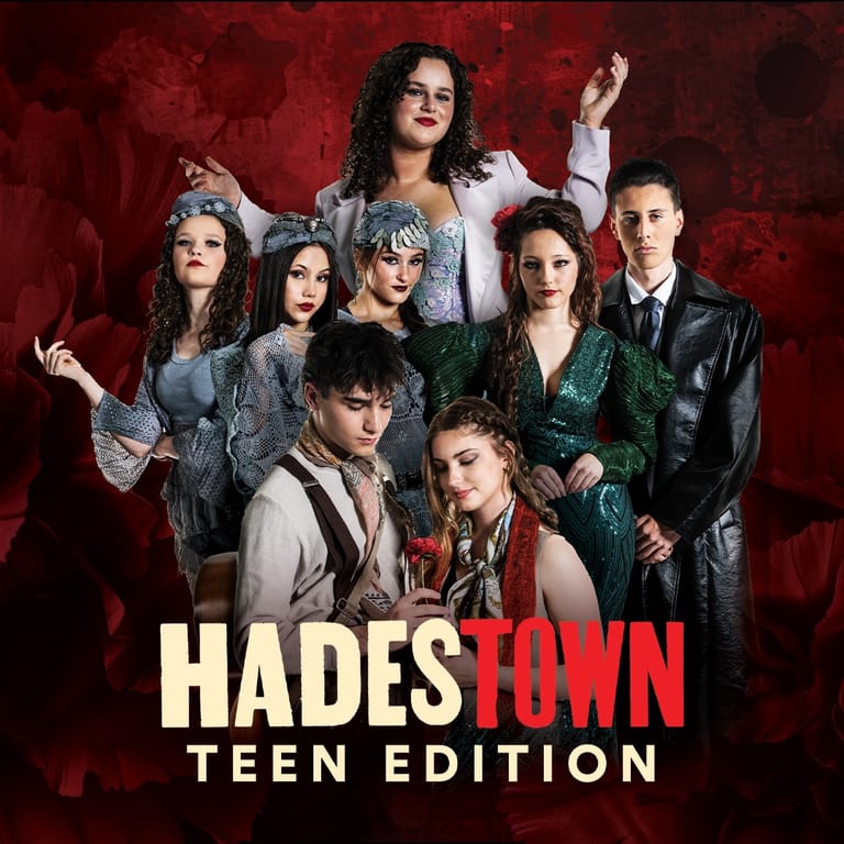 Eight young performers in dark clothing pose against a deep red background for Hadestown Teen Edition promotional image.