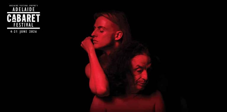 Two performers in profile, bathed in red stage lighting, during a dramatic theatre production.