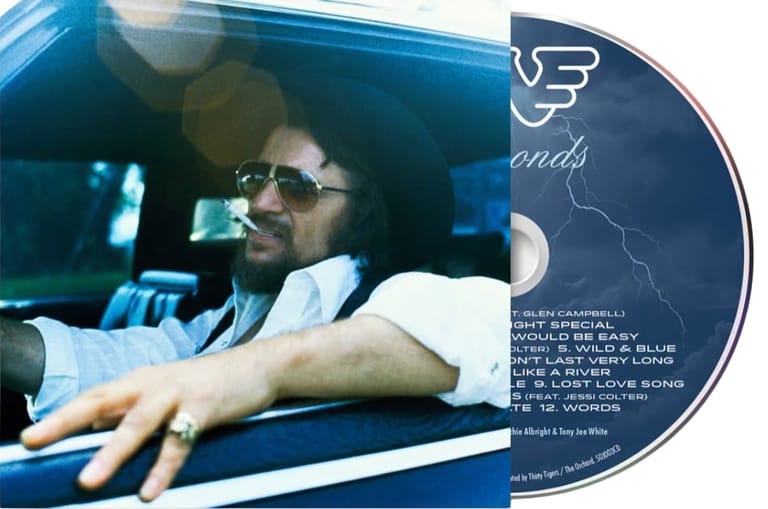Man wearing sunglasses at a DJ turntable with a music album cover displayed beside him.