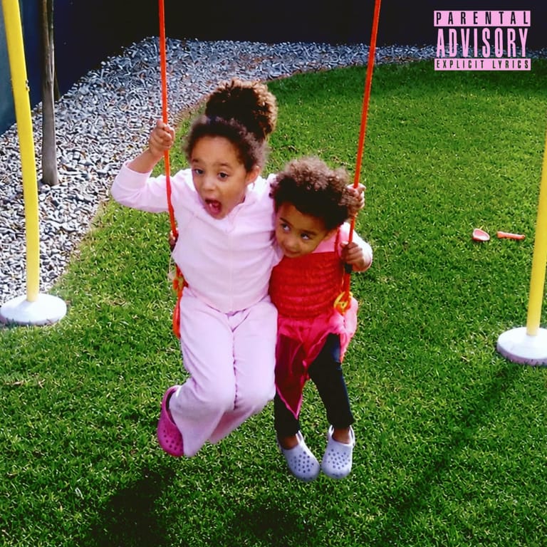 Two young children on a bright synthetic green lawn swinging from red ropes, with Parental Advisory label visible.