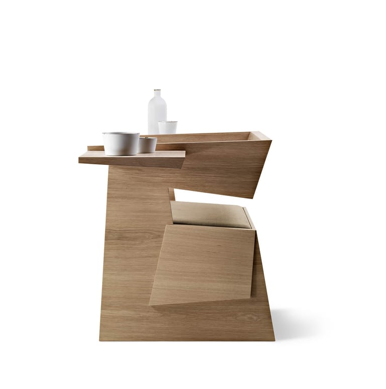 Geometric wooden side table with angular surfaces, metal containers, and a water bottle arranged on its top.