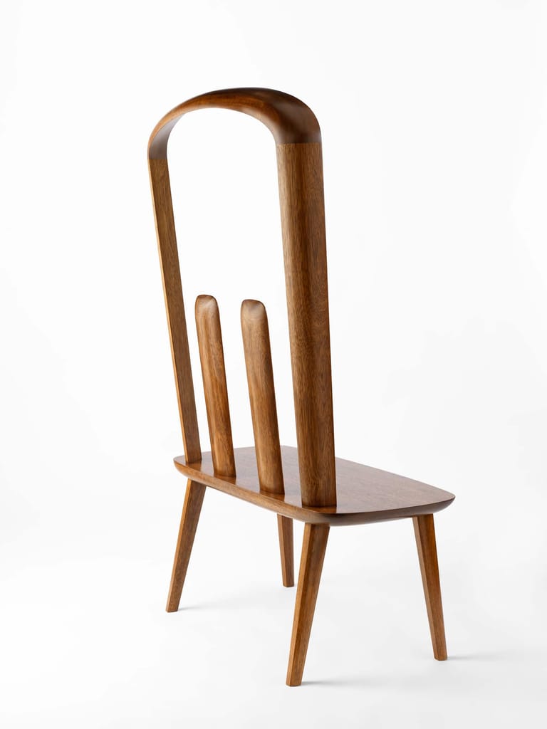 Wooden chair with tall curved backrest and tapered legs against white background.