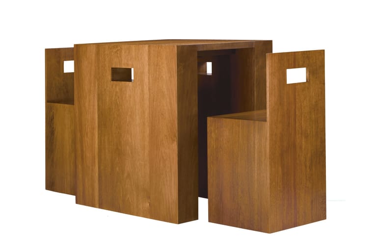 Wooden modular art installation with open compartments and small window cutouts arranged in a cuboid form.