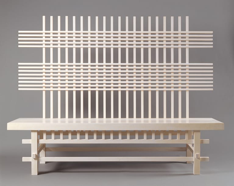 Minimalist wooden bench with slatted backrest design against grey background.