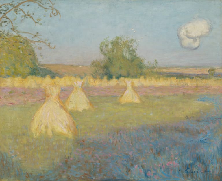 Haystacks scattered across a rural landscape with blue water and distant trees under a pale sky.