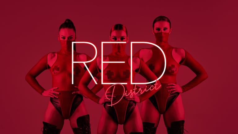 Three performers in red outfits posed against a crimson backdrop with neon "RED District" signage.