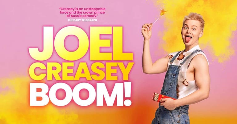 Joel Greasey in denim overalls against a vibrant pink and yellow gradient background with "BOOM!" text overlay.