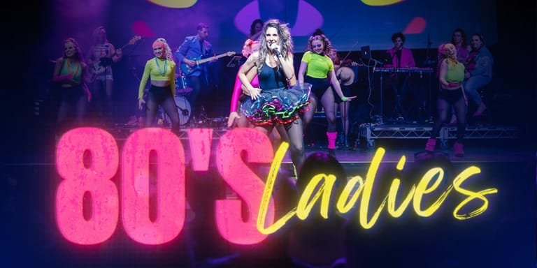 Performer in sequined costume centre stage with band and dancers bathed in neon pink and yellow stage lighting during 80's Ladies production.