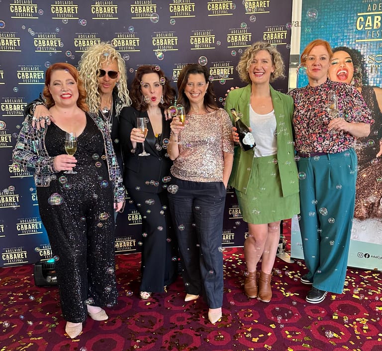 Seven women posing together on a red carpet at a Cabaret event premiere.