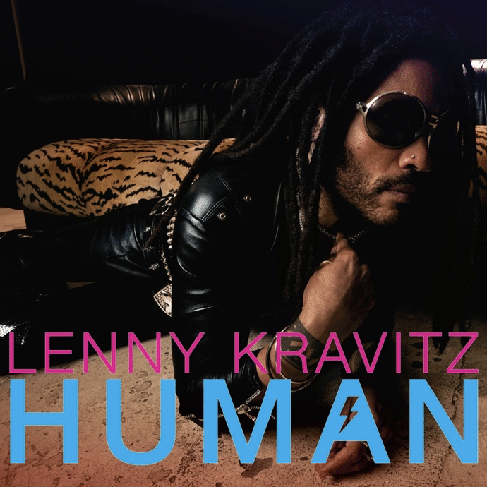 Man with dreadlocks and sunglasses wearing black leather jacket on leopard-print furniture.