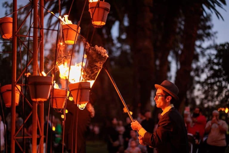 Person lighting red paper lanterns at dusk during an outdoor festival celebration.