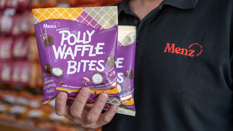 Person in Menz branded black shirt holding a box of Polly Waffle Bites confectionery.