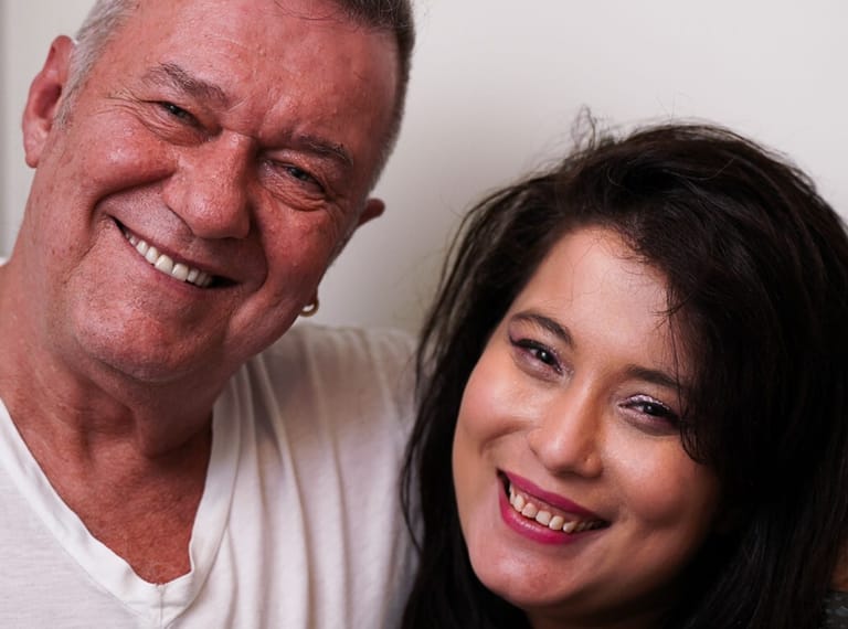 Two smiling people pose together against a white background for a portrait photograph.