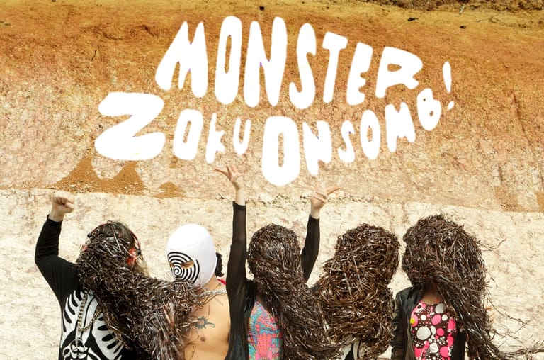 Five people with leafy foliage covering their heads stand beneath a "Monstera Zoologique" sign on a textured wall.