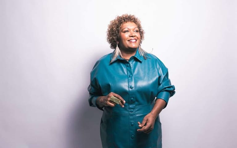 Person in a teal button-up shirt smiling against a white background.