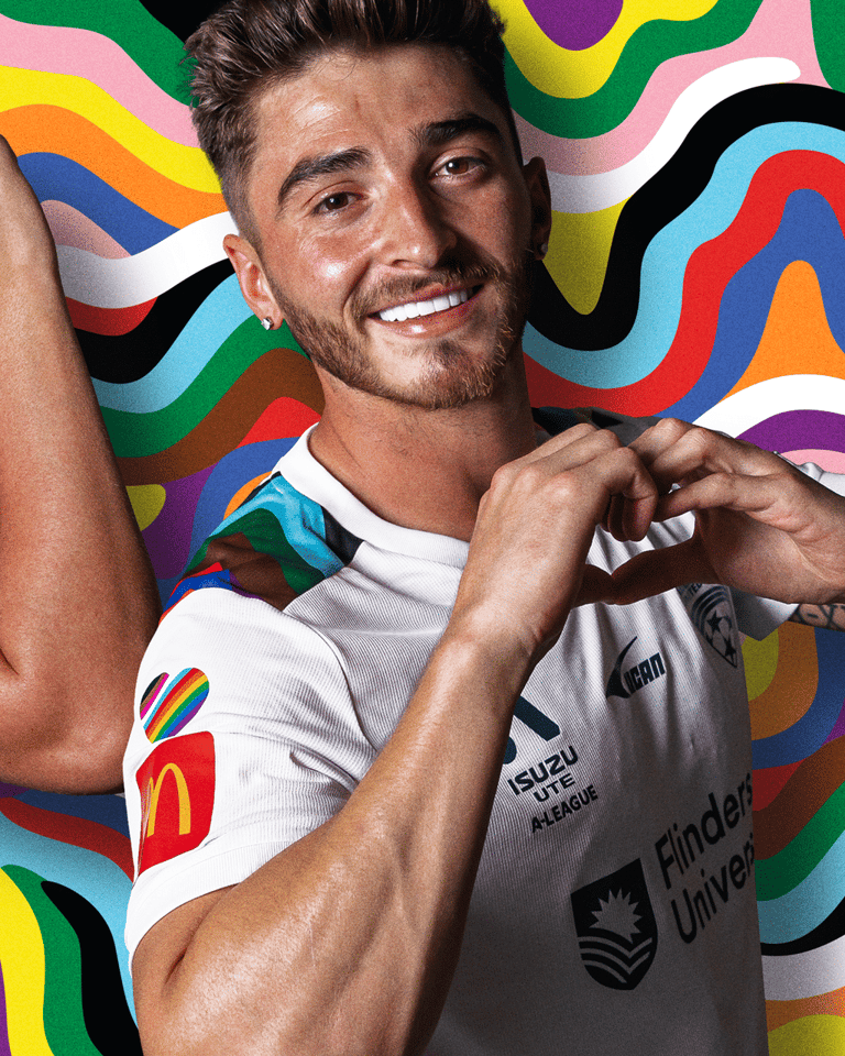 Man in white shirt smiling against a vibrant, multicoloured wavy abstract background.