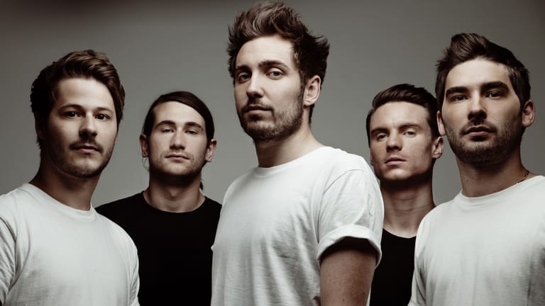 Five men in casual t-shirts posed against a neutral grey background.
