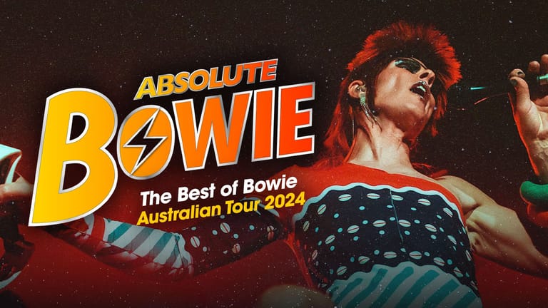 Performer in striped top and sunglasses under stage lighting during Absolute Bowie Australian Tour 2024.