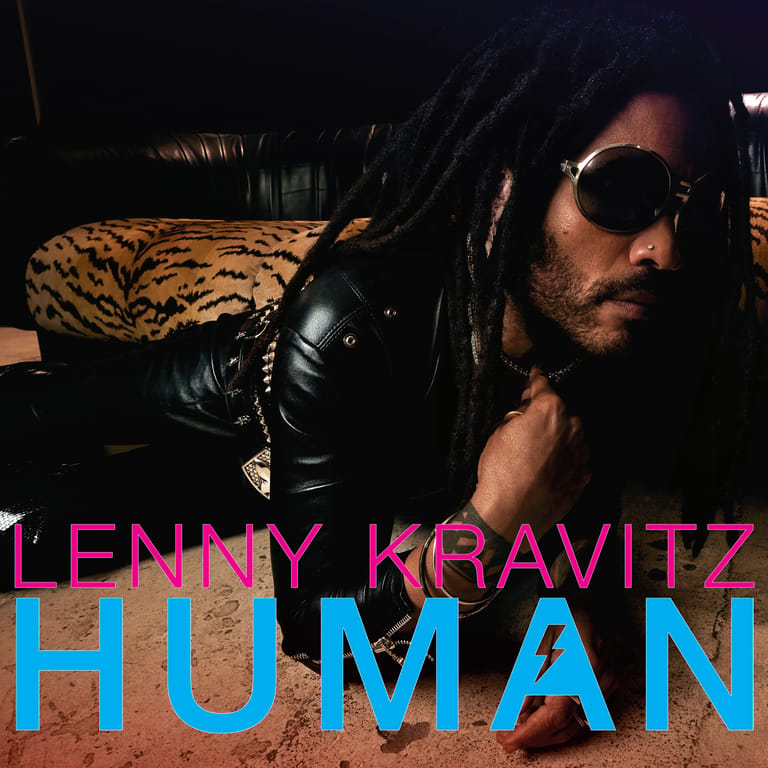 Artist wearing sunglasses and black leather jacket reclining on leopard-print fabric for album artwork.