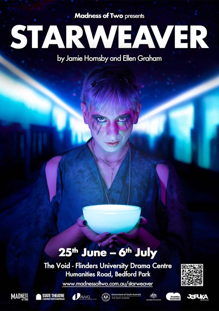 Performer with short purple-tinted hair holds a glowing white bowl against a backdrop of blue neon lights.