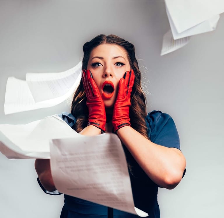 Woman in red gloves holding papers with shocked expression as documents fall around her.