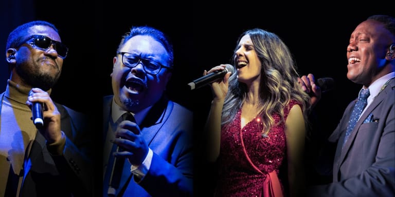 Four performers singing together on stage under blue and warm stage lighting.