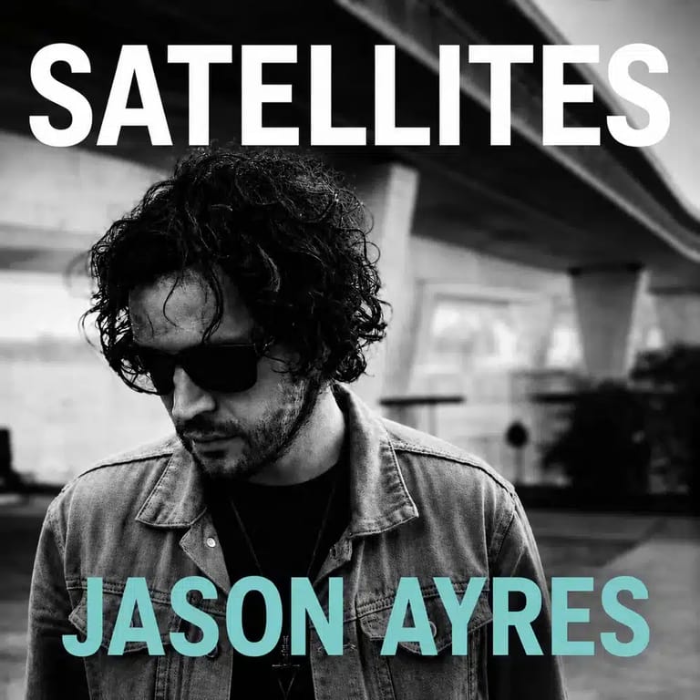Man wearing sunglasses and denim shirt in monochrome urban setting for Satellites album artwork.
