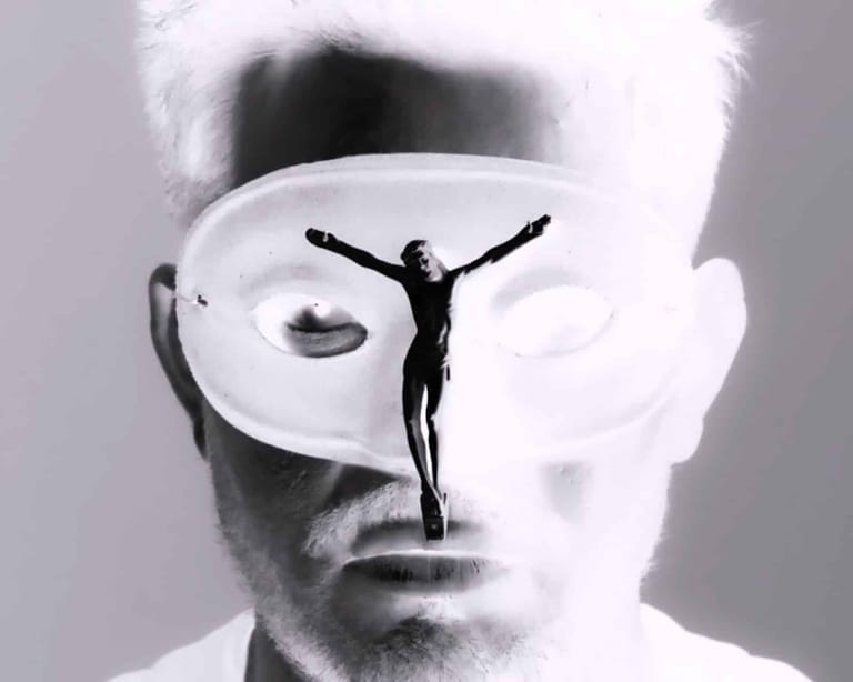 Figure with arms raised stands within a surreal circular aperture superimposed on a man's face in black and white.