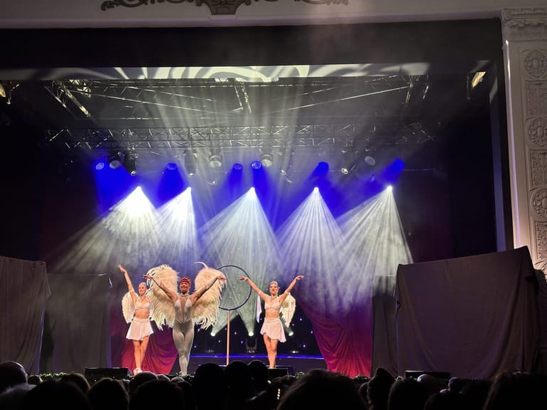 Performers in sparkly costumes stand centre stage under dramatic blue and white lighting during The Christmas Spectacular production.