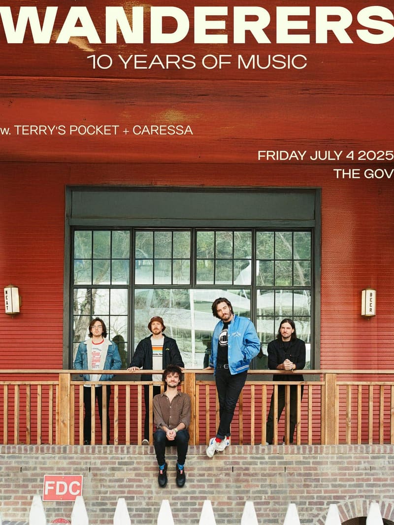 Five musicians stand and sit on a red brick building's front steps beneath a "Wanderers – 10 Years Of Music" banner.