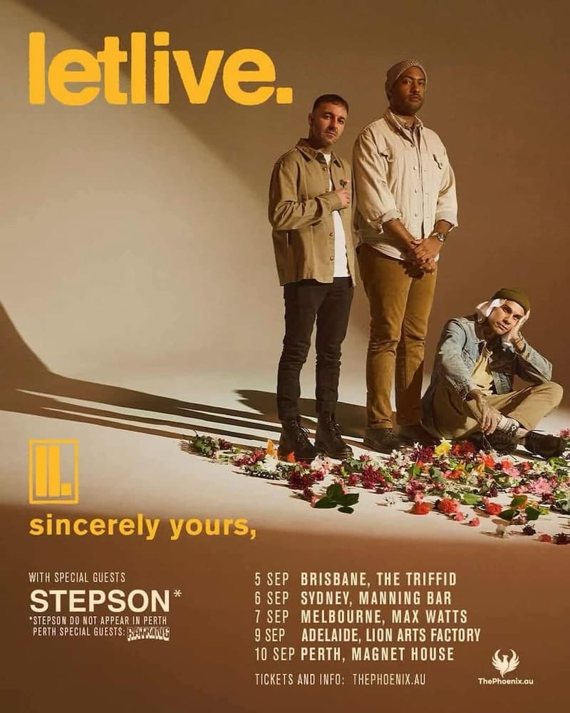 Three band members stand against a beige wall with scattered flowers at their feet, beside the letlive. tour poster.